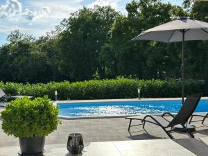 an umbrella and two chairs next to a swimming pool at Villa Olealis in Zatka Čepić