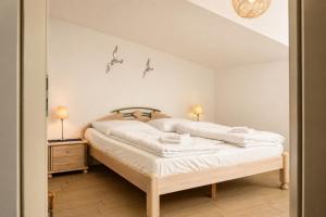 a bedroom with a bed with white sheets and two lamps at Ferienhaus Alisch Fewo 2 in Warnemünde