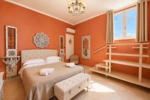 a bedroom with orange walls and a bed and a chandelier at Panorama Suites Noto - Adults Only in Noto