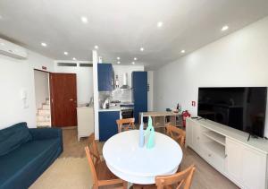 a living room with a white table and a kitchen at Casa na Aldeia in Melides