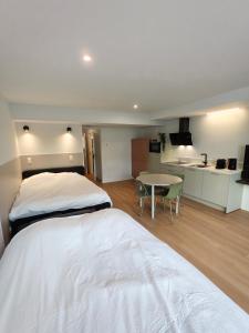 a bedroom with two beds and a table and a kitchen at Chez EdGare in Liège