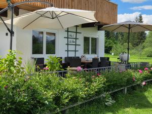 a house with two umbrellas and a table and chairs at Ferienhaus DaPfusterer in Bad Mitterndorf