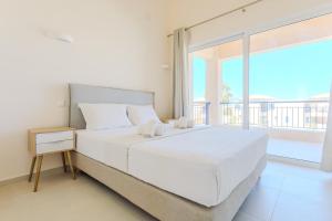a bedroom with a white bed and a large window at Resitour - Aphrodite Beachfront in Pírgos Psilonérou +110 photos