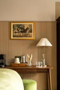 a table with a lamp and a painting of horses at The Swan in Arundel