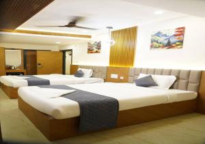 a hotel room with three beds in a room at DEVATA SUITES in Vijayawāda