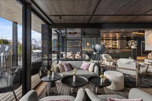 a living room with a couch and tables at TRIFORET alpin resort by Falkensteiner in Hinterstoder