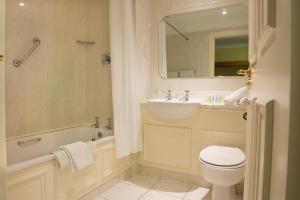 Tralee Benners Hotel في ترالي: حمام مع حوض ومرحاض وحوض استحمام