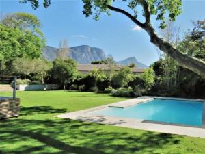 a backyard with a swimming pool and a grass yard at The Barn Style Cottage in Cape Town