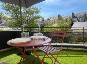 a red table and chair on a balcony with an umbrella at Appartement hyper Centre Rénové Terrasse & Parking in Tours