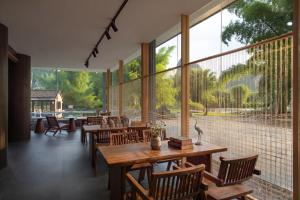 a restaurant with tables and chairs and large windows at L'Eau Vive de Qixi Meidi - Riverfront Infinity Pool & Log Cabin Cafe - Outdoor Cooking Class - Complimentary Shuttle within 8 Kilometers in Yangshuo