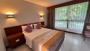 a bedroom with a bed with pink pillows and a window at โรงแรมฉัตรแก้ว in Ban Dan Chang