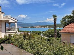 a house with a palm tree and a view of the water at Apartments Nevenka K. in Čižići