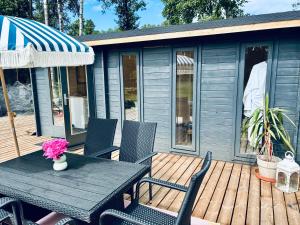 a table and chairs on a deck with a house at Haapsi Hideaway Garden Cabin in Haapsi