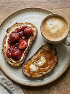a plate with two pancakes with strawberries and a cup of coffee at Haapsi Hideaway Garden Cabin in Haapsi