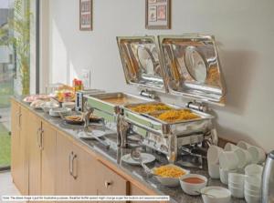 a buffet line with dishes of food on a counter at Hotel Luxury Villa - Near IGI Airport Mahipalpur New Delhi in New Delhi