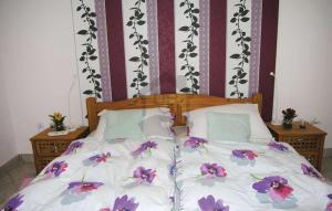 a bed with white sheets and purple flowers on it at CUKROS Villa in Cserkeszőlő +16 photos