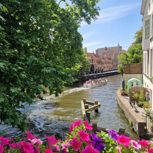 a boat on a river in a city with flowers at Authentiek Vakantiehuis Bos-en-Veld - Prive-tuin - Fietsvriendelijk vlakbij Brugge in Wingene +18 photos