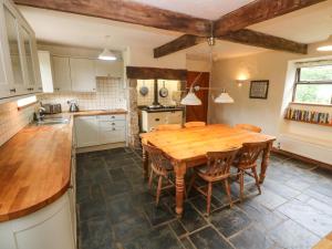 a kitchen with a wooden table and chairs at Swallow Cottage in Helston