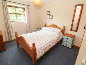a bedroom with a wooden bed and a mirror at Swallow Cottage in Helston