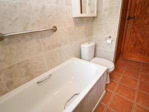 a bathroom with a bath tub and a toilet at Swallow Cottage in Helston +17 photos