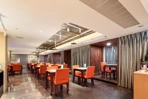 a dining room with tables and orange chairs at In One City Inn in Taichung