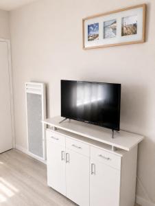 a living room with a flat screen tv on a white entertainment center at Studio - Pleine Mer - 1 avenue des Pays de Monts - 1-1 in Saint-Jean-de-Monts +3 photos