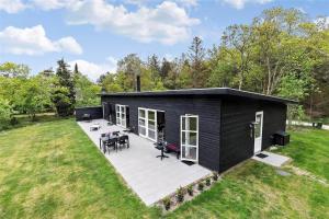 a black tiny house with a deck in a field at 8245-Knebel-Metholmvej-9 in Knebel +22 photos