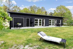 a black house with a bench in a yard at 8245-Knebel-Metholmvej-9 in Knebel