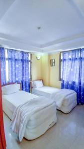 two beds in a room with blue curtains at Camp seleu in Dar es Salaam