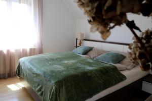 a bedroom with a bed with a green blanket on it at Lenz Stay - Ganzes Ferienhaus mit privatem Garten in Kaisersberg