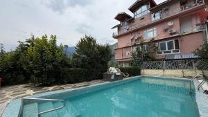 a swimming pool in front of a building at Countryside Himalayan Resort in Manāli