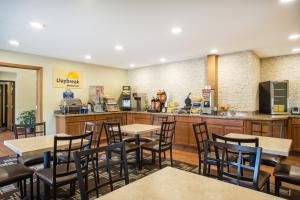 a restaurant with tables and chairs and a kitchen at Days Inn by Wyndham Evansdale Waterloo in Evansdale