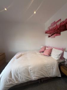 a bedroom with a white bed with pink pillows at Bel Palace in Hackbridge