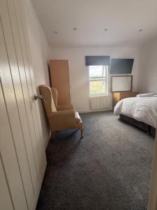 a bedroom with a bed and a chair and a window at Bel Palace in Hackbridge