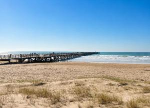 a pier on a beach next to the ocean at Studio - Pleine Mer - 1 avenue des Pays de Monts - 1-1 in Saint-Jean-de-Monts