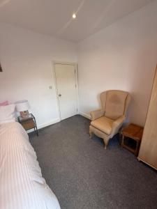 a bedroom with a chair and a bed and a door at Bel Palace in Hackbridge