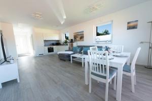 a living room with a table and chairs and a kitchen at Sonne & Sand Strandnahes Ferienhaus mit Whirlpool, Sauna & Wallbox in Büsum