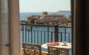 a view of the ocean from a balcony with a table and chairs at Corinthia St George's Bay in St. Julianʼs