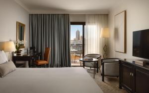 a hotel room with a large bed and a desk at Corinthia St George's Bay in St. Julianʼs