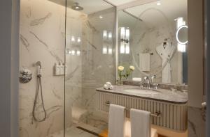 a bathroom with a shower and a sink and a mirror at Corinthia St George's Bay in St. Julianʼs