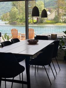 a dining room table with chairs and a large window at Modern lakefront apt with view - EV plug in Stryn