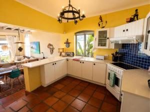 a kitchen with yellow walls and white cabinets at 'Cardamom House', Enchanting Vacation Home 2 min from the Beach, Sleeps 5 in Gordonʼs Bay