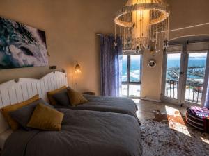 a bedroom with a large bed and a chandelier at 'Cardamom House', Enchanting Vacation Home 2 min from the Beach, Sleeps 5 in Gordonʼs Bay
