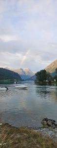 a rainbow over a lake with a boat in the water at Modern lakefront apt with view - EV plug in Stryn