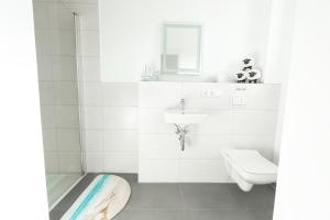 a white bathroom with a sink and a toilet at Sonne & Sand Strandnahes Ferienhaus mit Whirlpool, Sauna & Wallbox in Büsum +7 photos