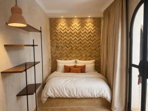 a bed in a small room with a wall at Riad Timoun in Agadir