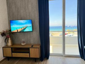 a room with a television on a wall with a beach at Beachfront Studio with Panoramic Sea View 2 in Ialysos