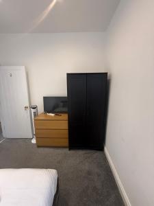 a bedroom with a black cabinet and a bed at Bel Palace in Hackbridge
