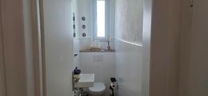 a white bathroom with a toilet and a window at Cozy city appartement in Forchheim