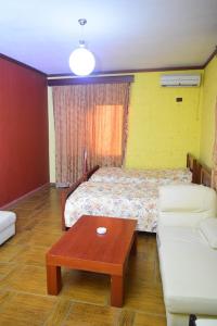 a room with a bed and a table and a couch at Hotel Deja in Tirana